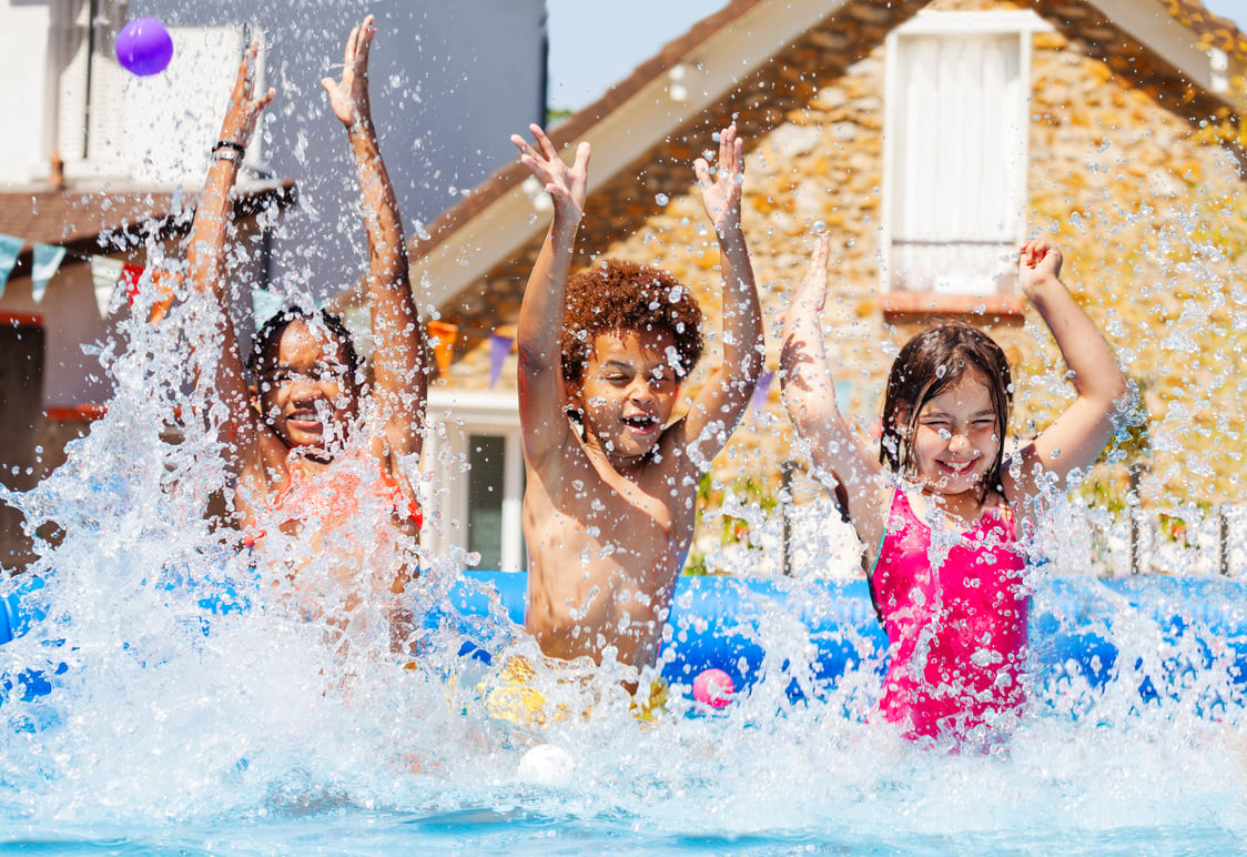 Portrait of Three Kids Splash Water in Garden Pool